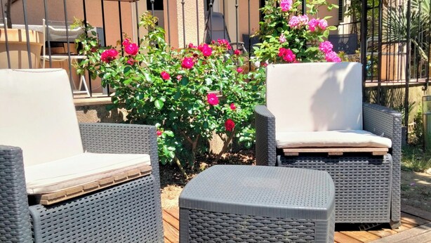 Zona patio con mobili in vimini e un molo in legno.