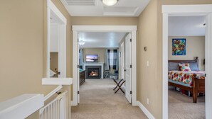 A hallway leading to a bedroom with a bed, a television, and a fireplace. - Spacious Family Friendly SE, Free Parking, A/C, Walk to food, Toy Room, Crib! (Portland)