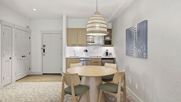 Una cocina moderna con gabinetes blancos, una mesa redonda de comedor y una lámpara colgante.