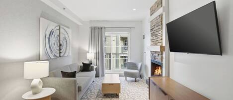A modern living room with a sofa, a coffee table, a TV, and a fireplace.