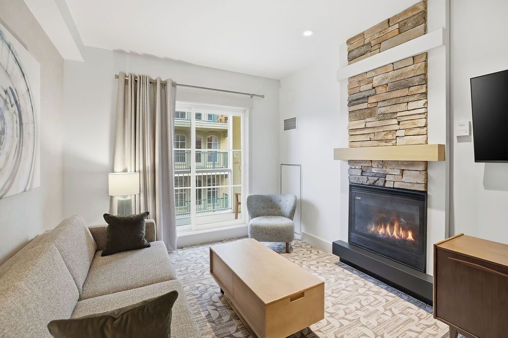 Una sala de estar moderna con chimenea, un sofá, un sillón y una mesa de centro.
