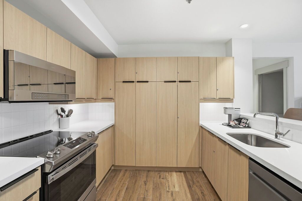 A modern kitchen with wooden cabinets, stainless steel appliances, and a white countertop.