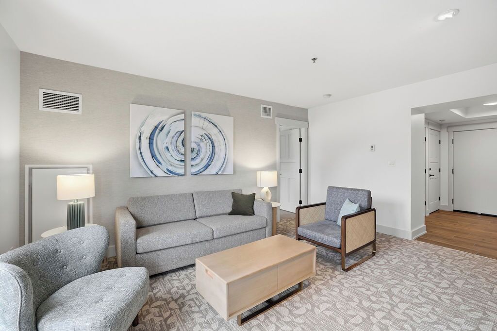 A modern living room with a grey sofa, a wooden coffee table, and a patterned rug.