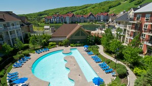 A swimming pool with lounge chairs and umbrellas, surrounded by buildings and greenery. - Blue Mountain Resort Mosaic Suites (The Blue Mountains)