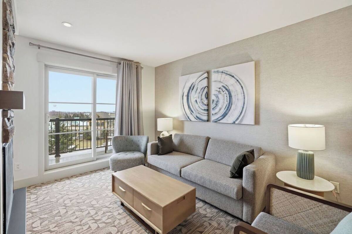 Une chambre d’hôtel avec une grande fenêtre, un canapé, une table basse et un tableau au mur.