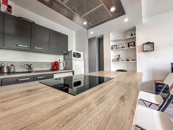 A modern kitchen with a central island, built-in appliances, and a dining area with chairs.