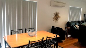 Comedor con mesa y sillas de madera, un cuenco decorativo y un aire acondicionado instalado en la pared.