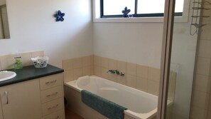 A bathroom with a bathtub, a sink, and a shower. - Kedah Central Retreat (COWES)