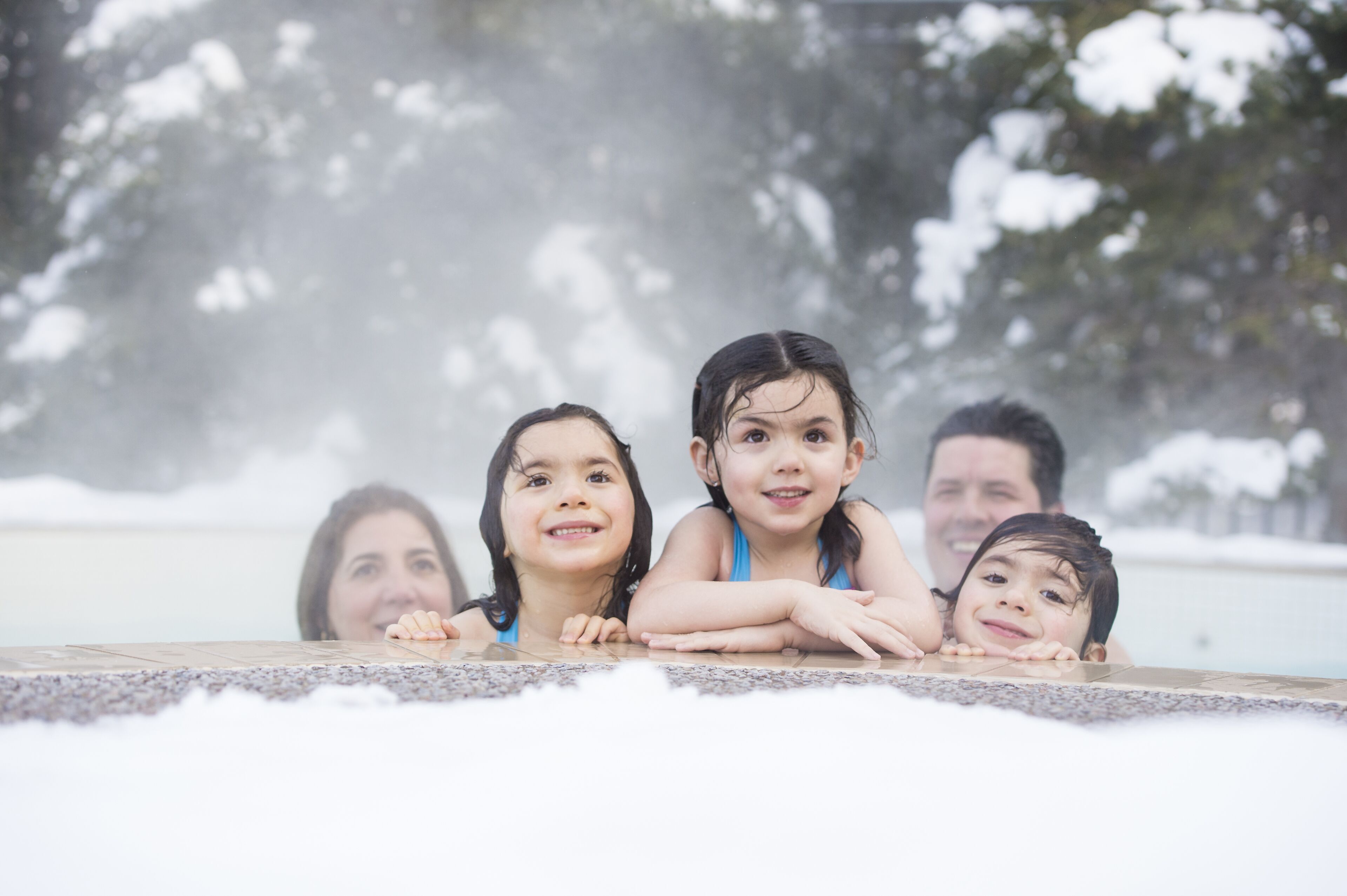 A group of people leaning on a pool edge with a snowy background.