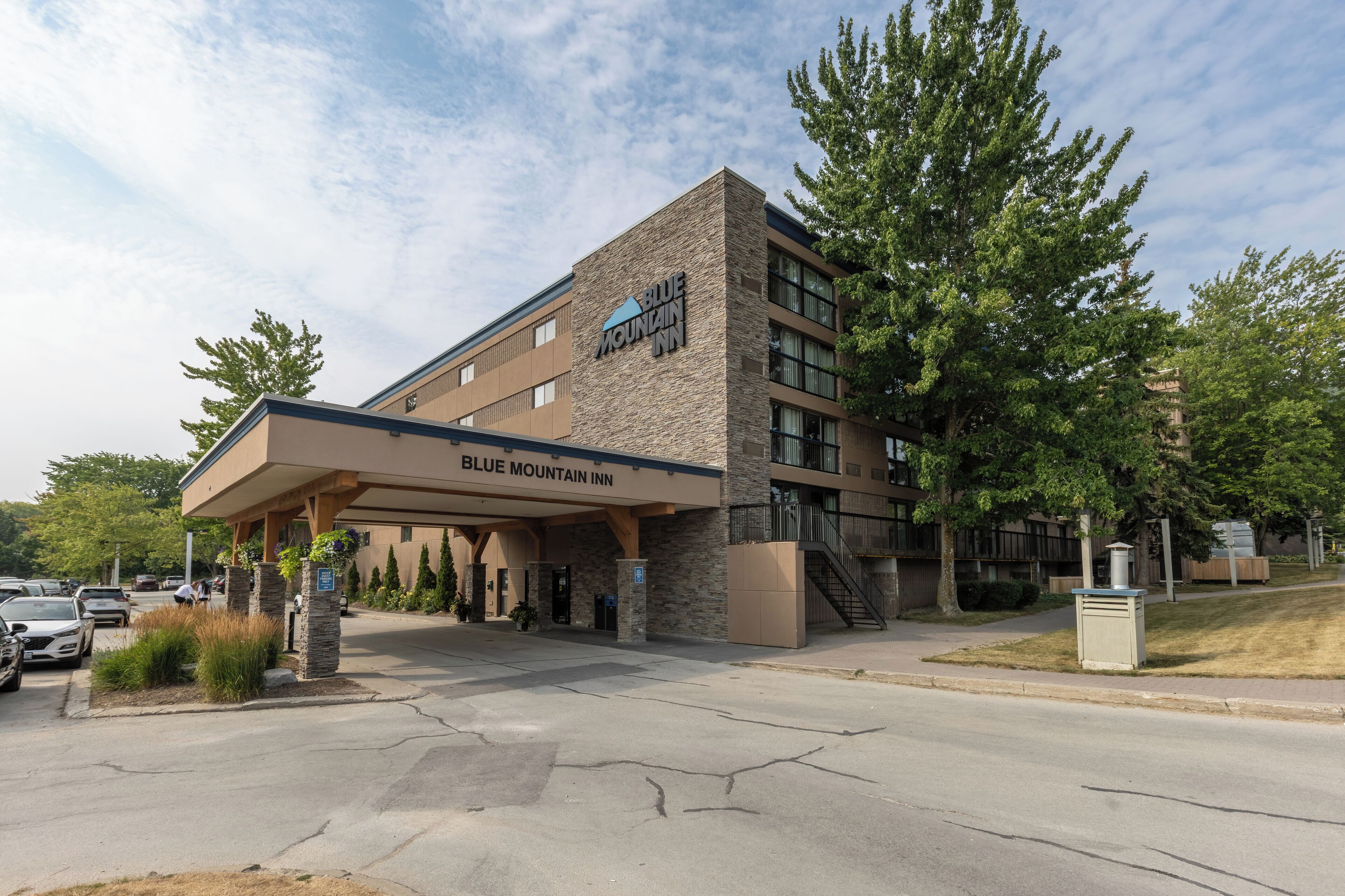 A Blue Mountain Inn building with a covered entrance, parking lot, and surrounding greenery.