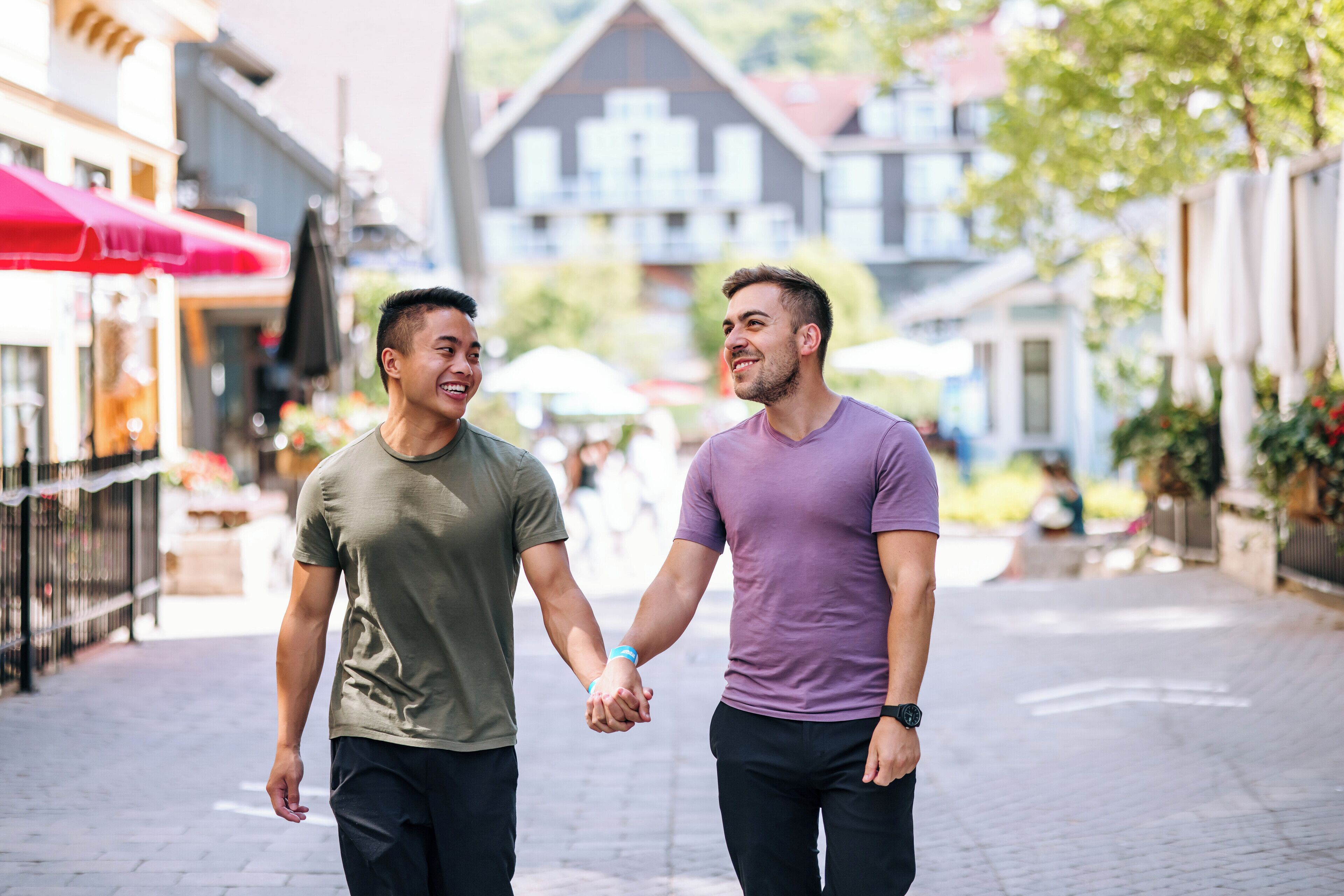 Two people holding hands walking down a cobblestone street.