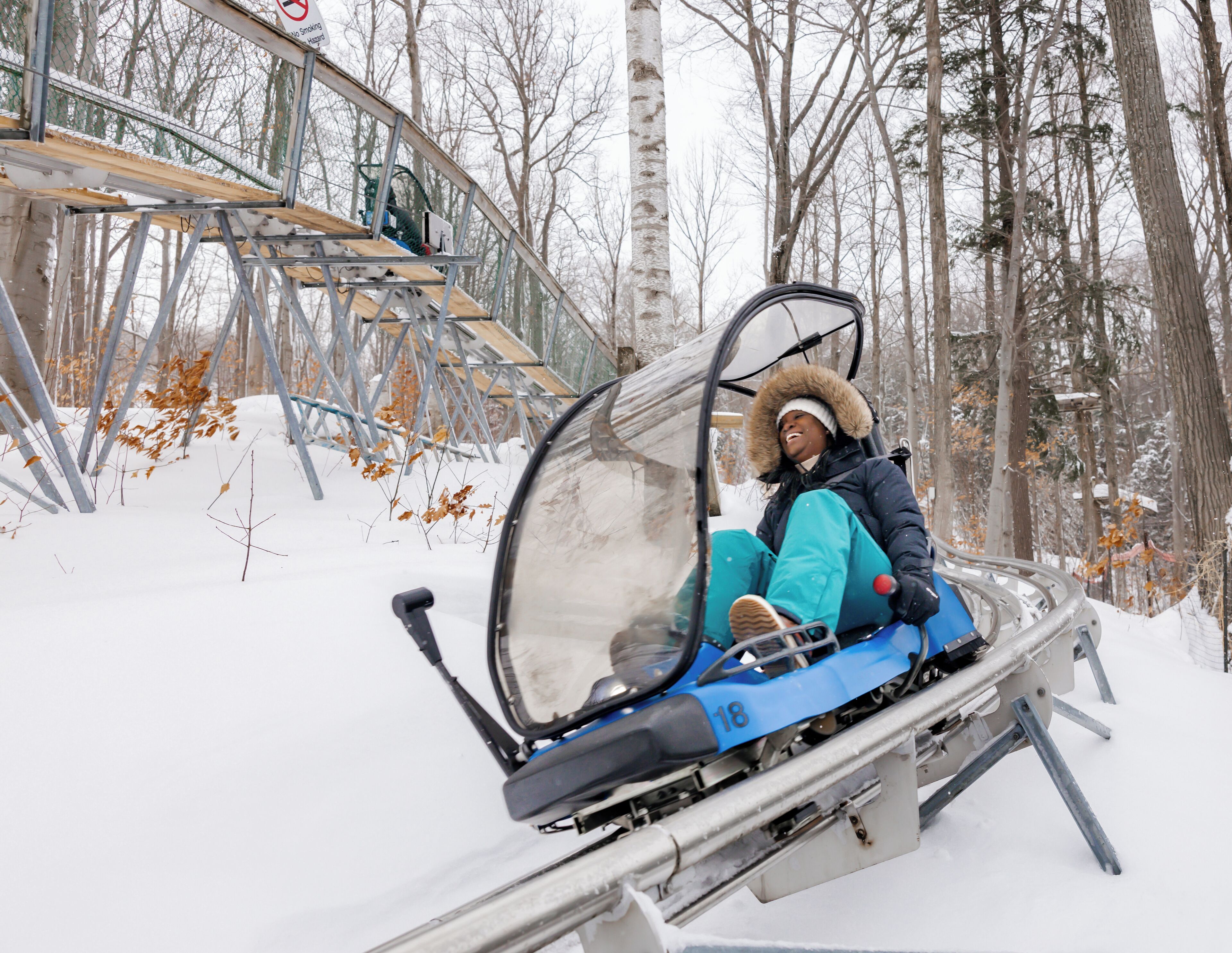 A person in a snow-covered forest on a sled.
