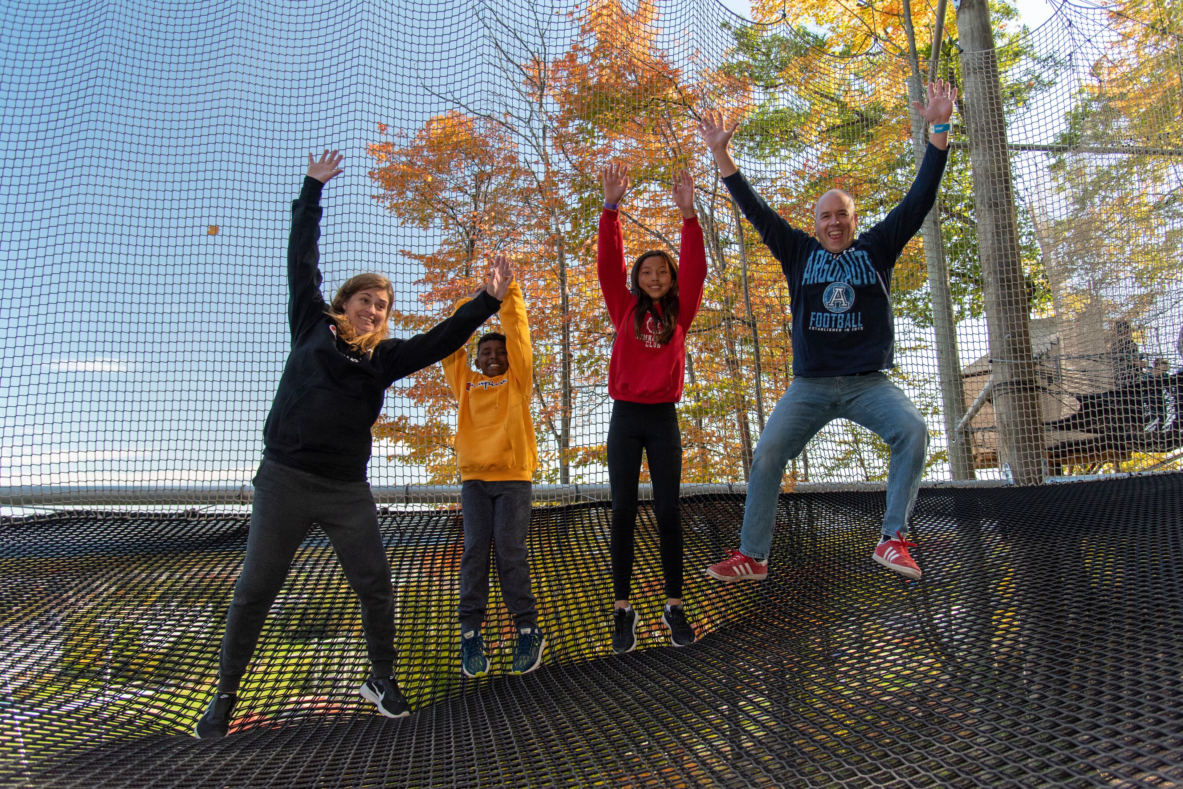A group of people jumping on a trampoline with a netted enclosure.