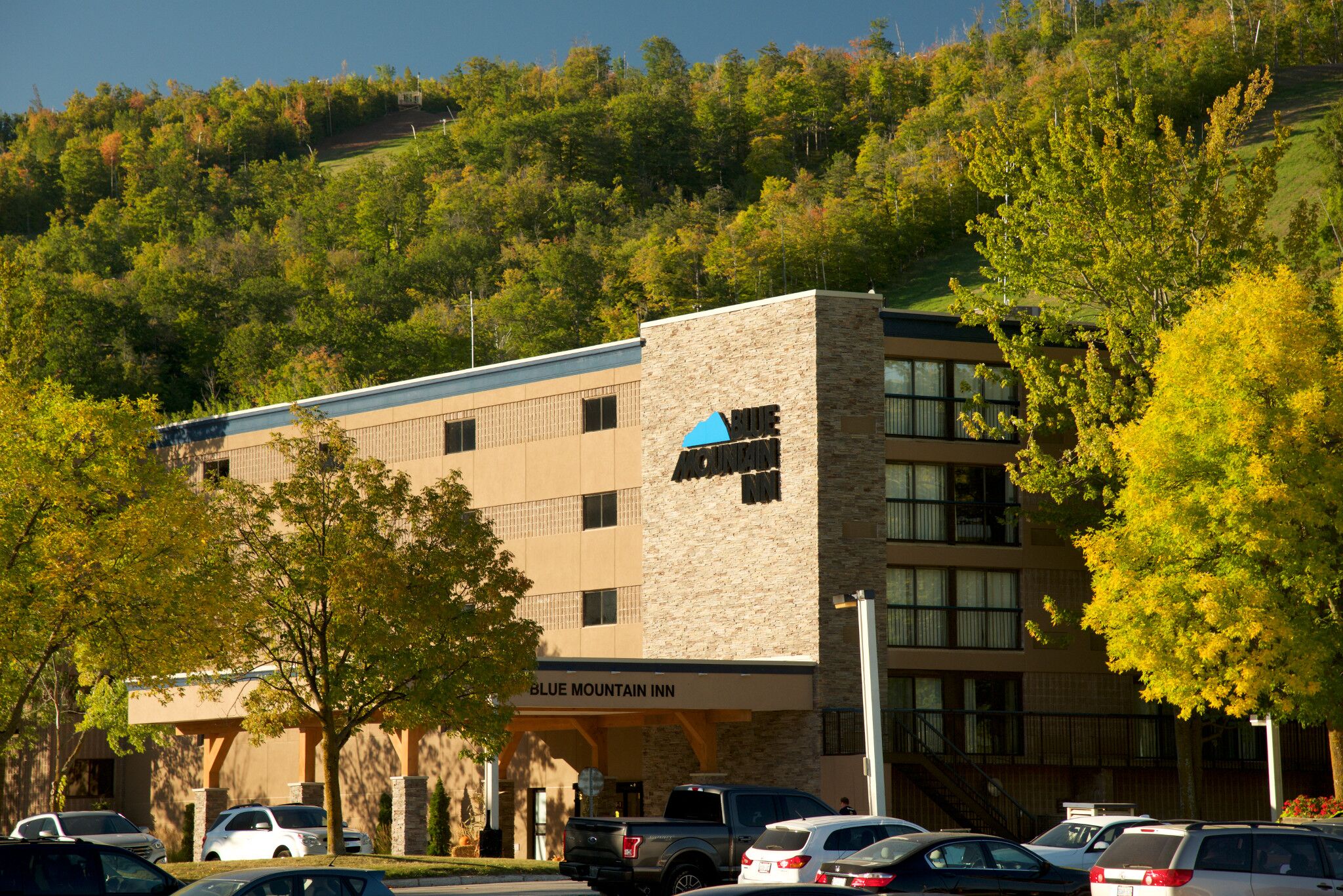 Un hôtel à la façade en pierre, avec plusieurs étages et un parking.