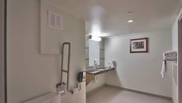 Un baño con inodoro, lavamanos, espejo y toallero.