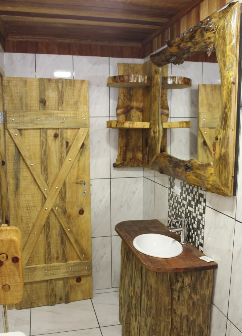 A rustic bathroom with a wooden door, a wooden sink vanity, and a mirror with a wooden frame.