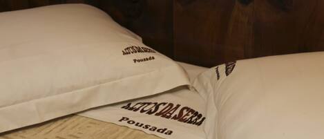 Una cama con almohadas que dicen "AETOS DA SERRA Pousada".