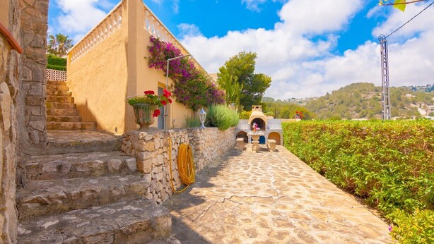 A stone staircase leading to a building with a tiled roof and a small outdoor oven.