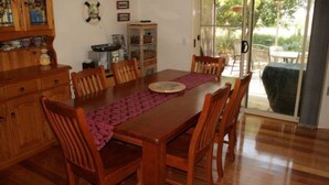 A dining area with a wooden table, chairs, and a purple placemat. - Silverleaves Beach and Spa Retreat (SILVERLEAVES)