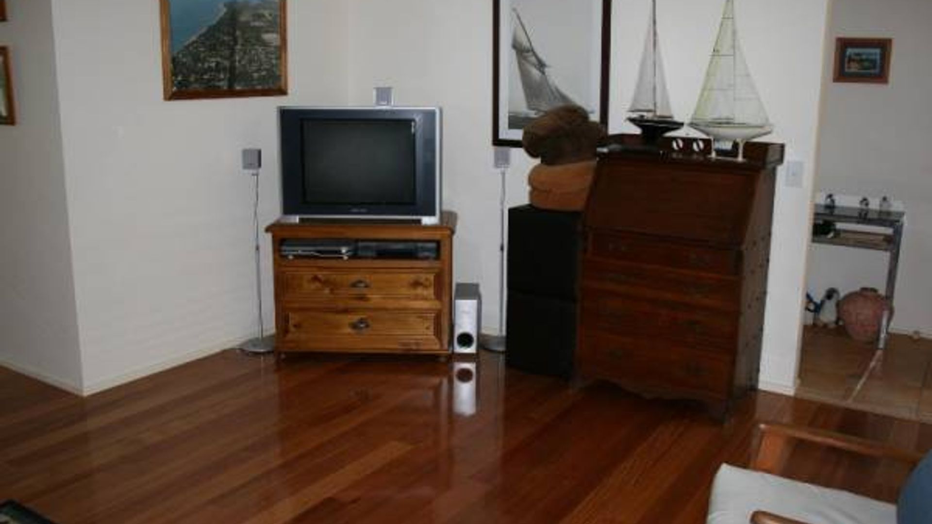 A living room with a wooden cabinet, a television, and a sailboat model.