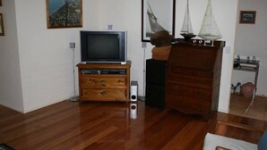A living room with a wooden cabinet, a television, and a sailboat model. - Silverleaves Beach and Spa Retreat (SILVERLEAVES)