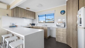 Une cuisine moderne dotée d’un grand îlot central, de meubles en bois, d’un four encastré et d’une fenêtre offrant une belle vue.