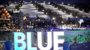 A snow-covered landscape with illuminated buildings and the word "BLUE" in large letters. - Blue Mountain Resort Home Collection (The Blue Mountains)