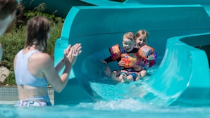 A water slide at a water park with a person and two children at the bottom. - Blue Mountain Resort Home Collection (The Blue Mountains)