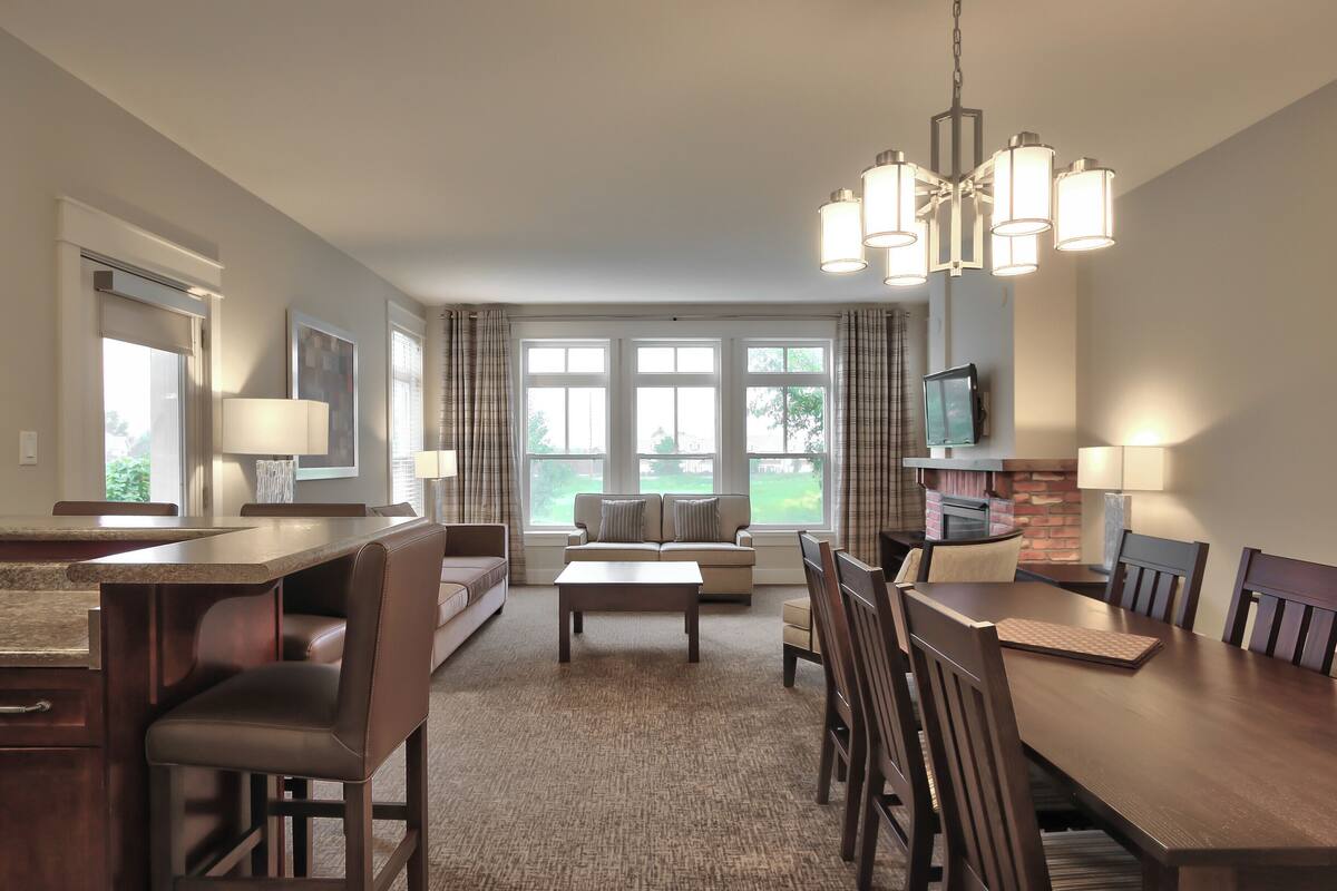 A spacious living room with a large dining table, comfortable seating, and a fireplace.