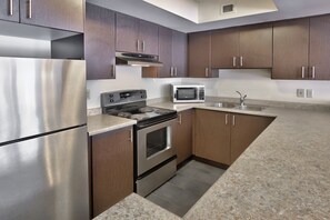 A modern kitchen with stainless steel appliances, wooden cabinets, and granite countertops. - Blue Mountain Resort Home Collection (The Blue Mountains)