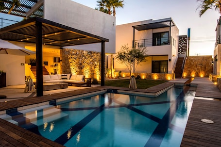 Una piscina al aire libre, sombrillas, sillones reclinables de piscina