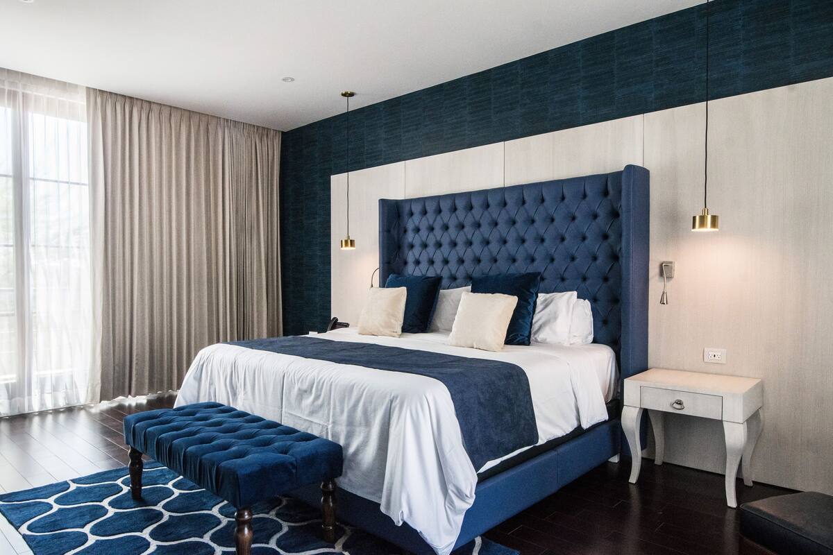 A modern bedroom with a large bed, a bedside table, and a bench.
