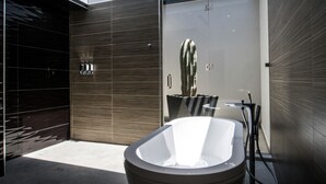 A modern bathroom with a freestanding bathtub, a glass shower enclosure, and a minimalist design. - Marsella 45 (Hermosillo)