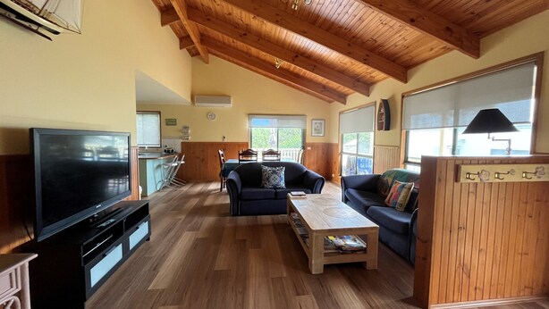 Een ruime woonkamer met houten vloeren, een televisie, een bank en een salontafel.