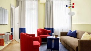 Un soggiorno moderno con una poltrona rossa, un divano marrone e un tavolino laterale blu.