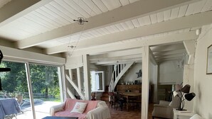 Ein großzügiger Wohnbereich mit hoher Decke, ein Essbereich und eine Treppe, die in eine andere Ebene führt.