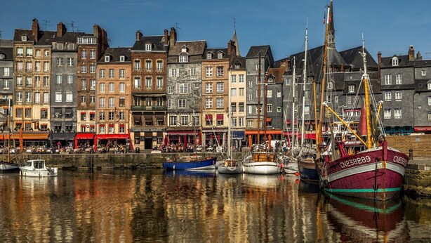 Ein Hafen mit vertäuten Booten und Gebäuden im Hintergrund.