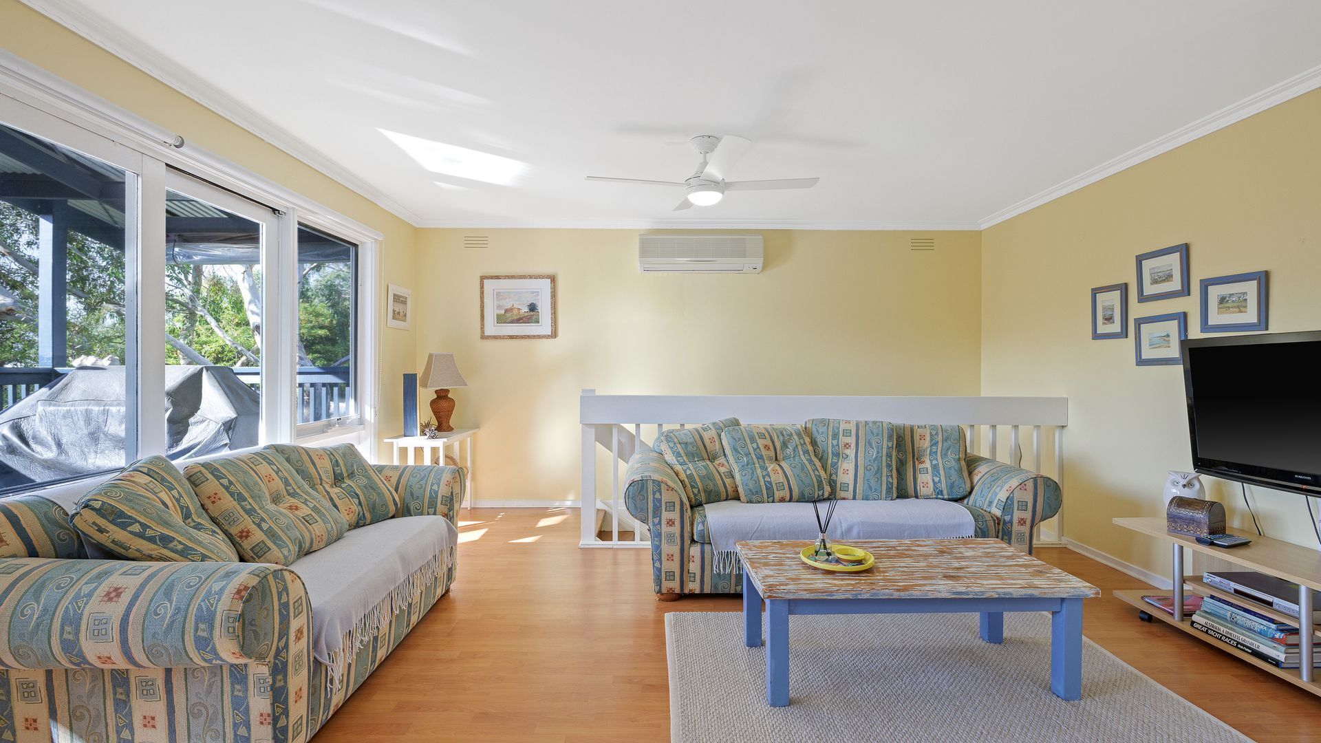 A living room with a sofa set, a coffee table, a TV, and a ceiling fan.