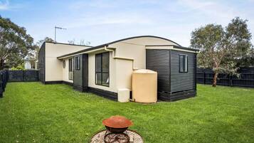A modern mobile home with a curved roof, a large water tank, and a well-maintained lawn.