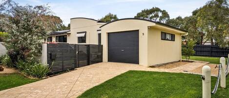 A modern two-story house with a garage, a paved driveway, and a well-maintained lawn.