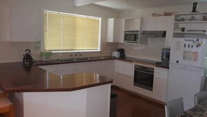 Cocina compacta con armarios blancos, microondas, tostadora y refrigerador.