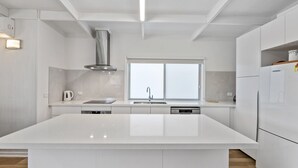 Een moderne keuken met een groot kookeiland, roestvrijstalen apparatuur en een raam dat voor natuurlijk licht zorgt.