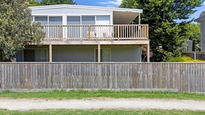 Een tweelaags huis met een balkon, een houten hek en een gazon.