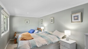 Une chambre avec deux lits, une table de chevet avec une lampe et un tableau encadré au mur.