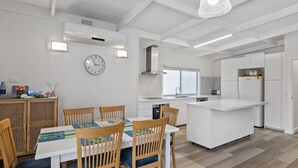 Een moderne keuken met witte kasten, een centraal eiland en een eethoek met houten stoelen en een tafel.