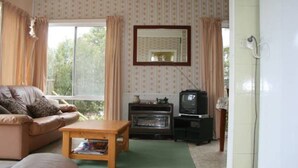 A living room with a sofa, a coffee table, a television, and a fireplace. - Salt On Seacombe (VENTNOR)