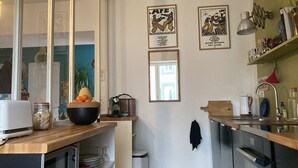 Et moderne køkken med en træbordplade, vask og komfur. To billeder hænger på væggen, og der er et spejl over vasken.