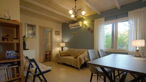 Una sala de estar acogedora con un sofá, sillas, una mesa de comedor y una estantería.