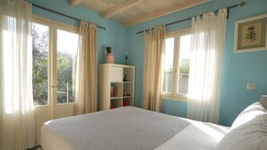 Un dormitorio con una cama grande, un armario blanco y una ventana con cortinas.