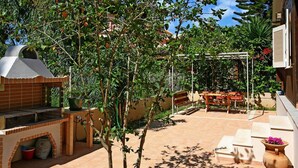 Un área de patio al aire libre con una parrilla de ladrillo, una mesa de madera y una pérgola.